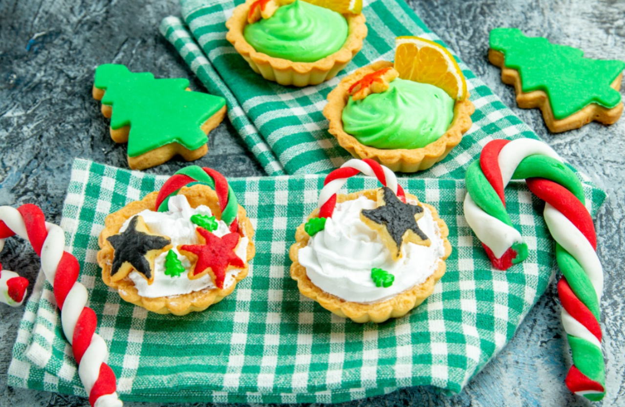 vista-inferior-de-tortinhas-de-natal-pequenas-doces-de-natal-na-toalha-de-mesa-quadriculada-branca-verde-na-mesa-cinza.png